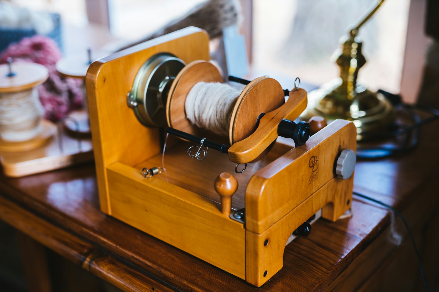 Wooden spinning wheel with wool on a dark table.